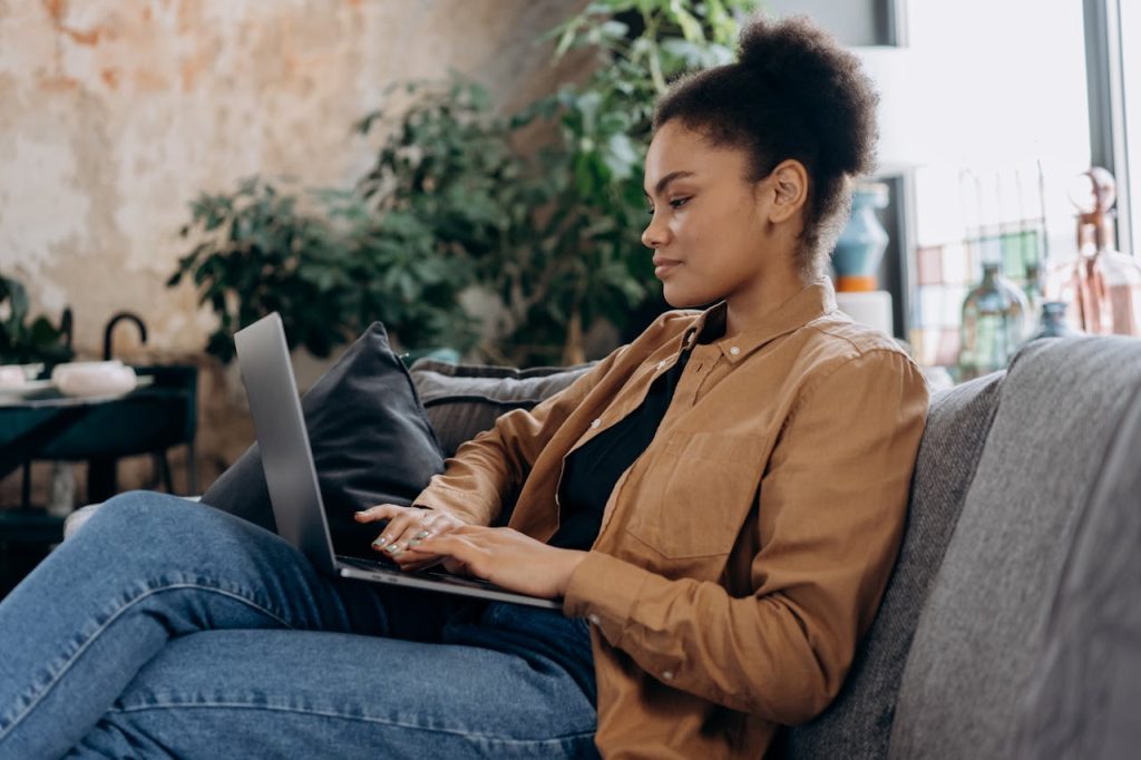 Home A young woman in casual clothing works on her laptop in a cozy home office setting.